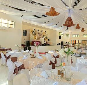 un salón de banquetes con mesas blancas y sillas blancas en RedDoorz Covelandia Garden Resort Nueva Ecija, 