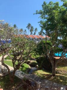 a garden with trees and a building in the background at DYNASTY MUINE RESORT in Ấp Thiện Phước