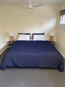 a bedroom with a large blue bed with two chairs at Lyndoch Hotel in Lyndoch