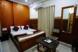 a bedroom with a bed and a table and a mirror at HOTEL PRAKAASH RESIDENCY in Mysore