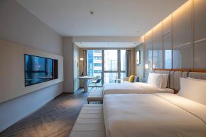 重慶市にあるVoco Chongqing Chaotianmenのベッド3台とテレビが備わるホテルルームです。