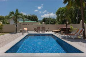 een zwembad met stoelen en een tafel en een patio bij Villa Confort in Grand'Anse Praslin