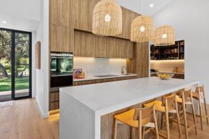 a kitchen with a white counter and wooden cabinets at Moggs Creek Luxury Escape in Aireys Inlet