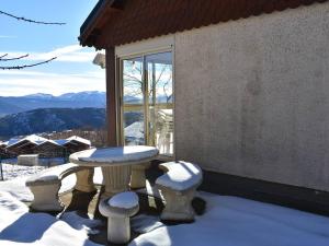 a table and two stools on a balcony with snow at Chalet Font-Romeu-Odeillo-Via, 5 pièces, 6 personnes - FR-1-580-39 in Font-Romeu-Odeillo-Via