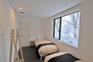 1 dormitorio con 2 camas y ventana en Myoko Apartments en Akakura