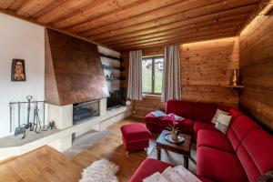 a living room with a red couch and a fireplace at Chalet Carpe Diem in Kaprun