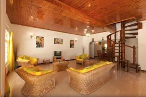 sala de estar con sillas de mimbre y escalera en Villa Confort, en Grand'Anse Praslin