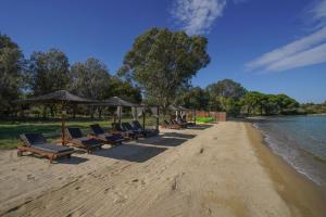 a row of chairs and umbrellas on a beach at Serenity Estate in Ormos Panagias