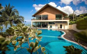 a villa with a swimming pool in front of a house at KaiBaeBeach GrandView in Trat