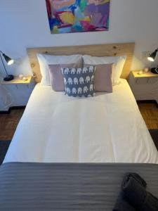 uma cama grande com lençóis brancos e almofadas em Acogedor y soleado apartamento recién amueblado en Gijón em Gijón