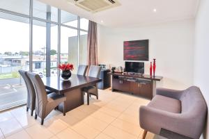 a living room with a table and chairs and a television at Indulge Apartments - Langtree in Mildura