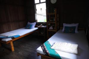 two twin beds in a room with a window at Bann Chi Homestay in Ban Pak Nam