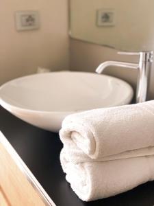 La salle de bains est pourvue d'un lavabo blanc et de serviettes sur un comptoir. dans l'établissement La Villa - Luxury Guest House, à Trente