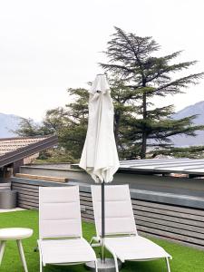 two white chairs and an umbrella on a patio at La Villa - Luxury Guest House in Trento