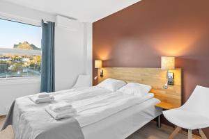 Marina Hotel Lofoten في سفولفير: غرفة نوم بسرير ابيض كبير ونافذة