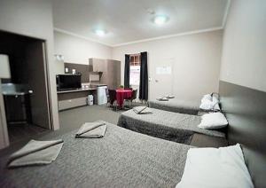 um quarto de hotel com três camas e uma mesa em Bluestone Motor Inn em Tennant Creek