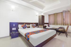 a hotel room with a large bed and a chair at FabHotel Skyland in Ahmedabad