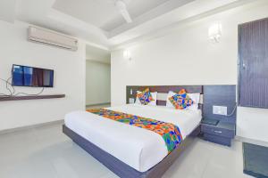 a white bedroom with a bed and a tv at FabHotel Skyland in Ahmedabad