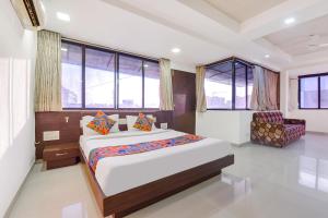 a bedroom with a bed and a chair and windows at FabHotel Skyland in Ahmedabad