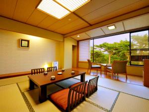 a dining room with a table and chairs and a window at Jodogahama Park Hotel in Miyako