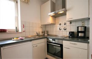 una cucina con lavello e fornello forno superiore di Ferienanlage Neuschwansteinblick Ferienwohnung 108 a Füssen Altre 13 foto