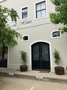 a white building with a black door and two plants at Luxury Franschhoek getaway next to Winetram in Franschhoek