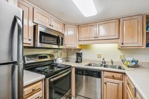 a kitchen with wooden cabinets and a stainless steel refrigerator at Holiday Surf & Racquet 614 Condo in Destin