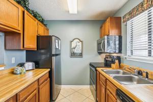 La cuisine est équipée d'armoires en bois et d'un réfrigérateur en acier inoxydable. dans l'établissement Sandpiper Cove 7201 Destin Condo, à Destin