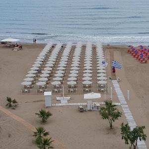un montón de sombrillas blancas en la playa en Kyma Suites Beach Hotel, en Rethymno