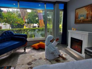 a person sitting on the floor in a living room holding a wine glass at Çetinel Otel in Adana