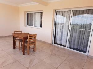 a wooden table and chair in a room with windows at HOTEL MENABE in Morondava