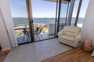 a living room with a chair and a view of the ocean at Sunrise @ the Point - Lovely 2 bdr unit with Pool in Soldiers Point