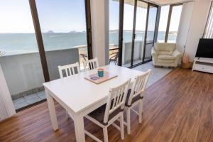 uma mesa e cadeiras brancas com vista para o oceano em Sunrise @ the Point - Lovely 2 bdr unit with Pool em Soldiers Point