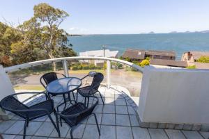a table and chairs on a balcony with a view of the ocean at Sunrise @ the Point - Lovely 2 bdr unit with Pool in Soldiers Point