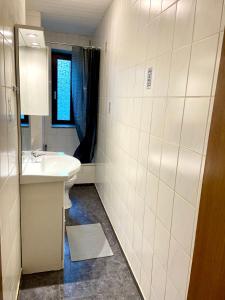 uma casa de banho branca com um lavatório e um espelho em Core Rooms - Apartment Oberhausen em Oberhausen