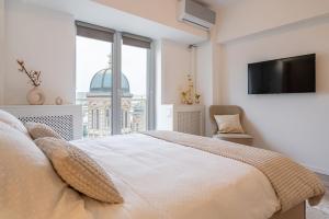 a bedroom with a bed and a tv and a window at Style and view Bucharest city center aparthotel in Bucharest