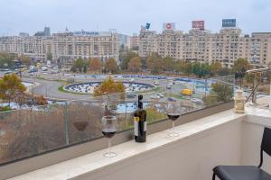 two glasses of wine on a balcony with a view of a city at Style and view Bucharest city center aparthotel in Bucharest
