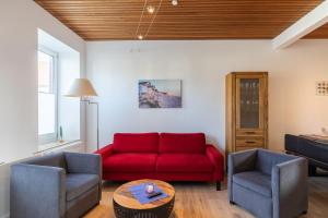 a living room with a red couch and two chairs at Haus Relax, Whg 3 in Duhnen
