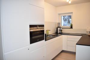 a kitchen with white cabinets and black counter tops at Allod (369 St) Whg. Nr. 402 in Lenzerheide