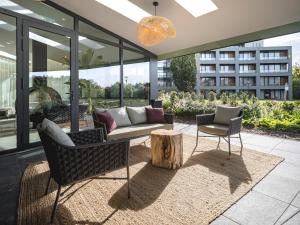 een patio met een bank en stoelen en een boomstronk bij Van der Valk Hotel Heerlen in Heerlen