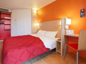 Habitación de hotel con cama roja y escritorio. en Premiere Classe Orleans Ouest - La Chapelle St Mesmin, en La Chapelle-Saint-Mesmin