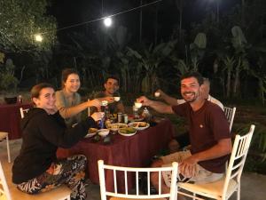 Eine Gruppe von Menschen, die an einem Tisch sitzen und Essen essen. in der Unterkunft Bee Lucky Homestay in Cát Bà