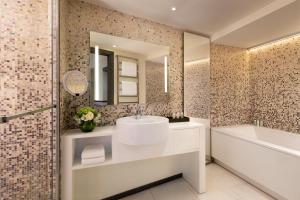 uma casa de banho com um lavatório, uma banheira e um espelho. em Hôtel de Paris Saint-Tropez em Saint-Tropez