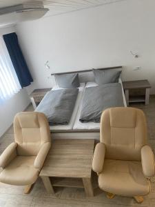 1 Schlafzimmer mit einem Bett und 2 Stühlen in der Unterkunft Hotel Braunlage in Braunlage