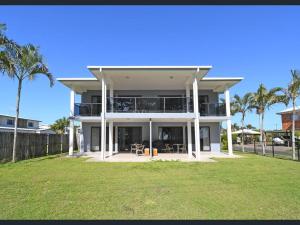 une grande maison blanche avec des palmiers devant elle dans l'établissement 3 Seacrets at Shelly, à Urangan