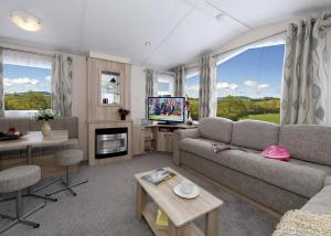 uma sala de estar com um sofá e uma televisão em Eastern Beach Caravan Park em Caister-on-Sea
