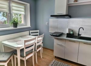 een keuken met een tafel en stoelen en een wastafel bij Apartament Za Potokiem in Groń