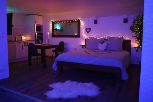 Dormitorio con cama con iluminación púrpura en Love room Unique - Sauna / Jacuzzi en Charleville-Mézières