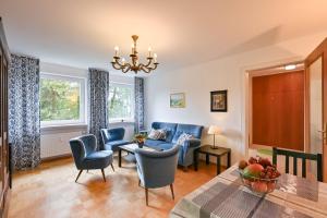 uma sala de estar com cadeiras azuis e uma mesa em Ferienwohnung Landhaus Helga unterm Schloss em Schwangau