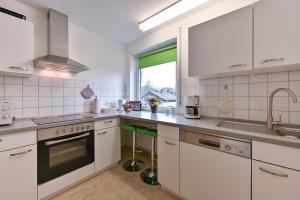 a kitchen with white cabinets and a sink and a window at Ferienwohnung Landhaus Helga unterm Schloss in Schwangau